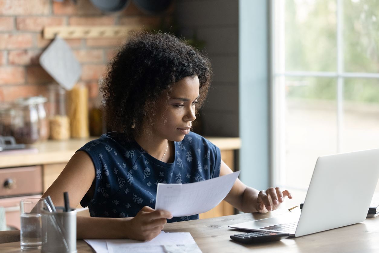 A woman sitting at her desk, making calculations on her laptop