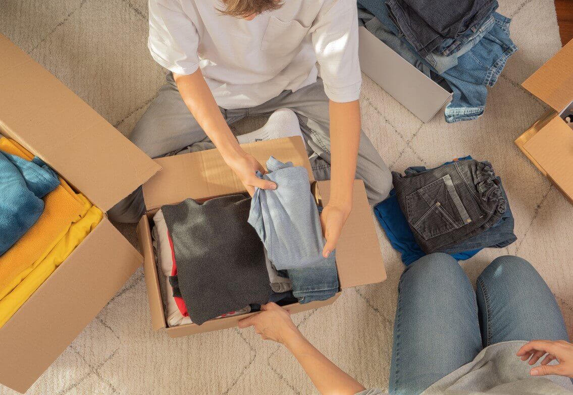 A family packing clothes into boxes.