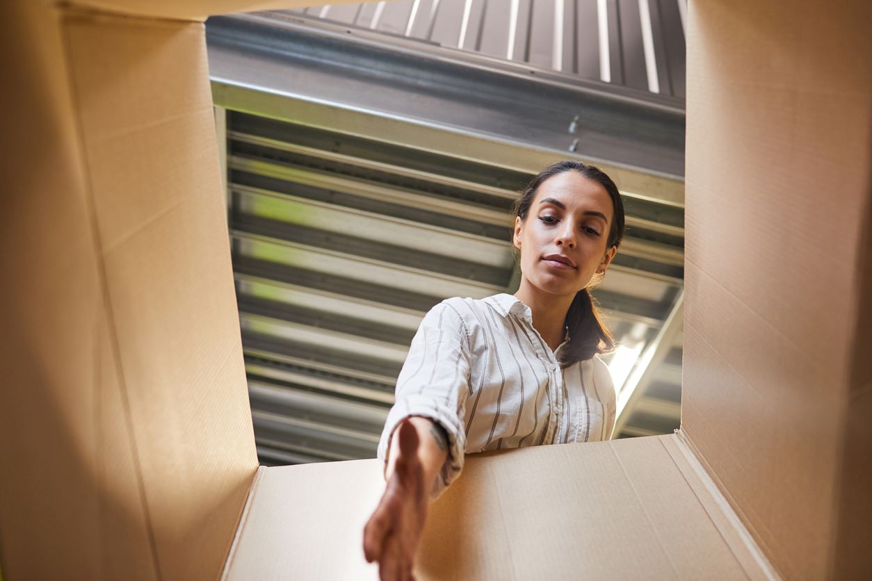 A POV shot of a woman reaching into a cardboard box