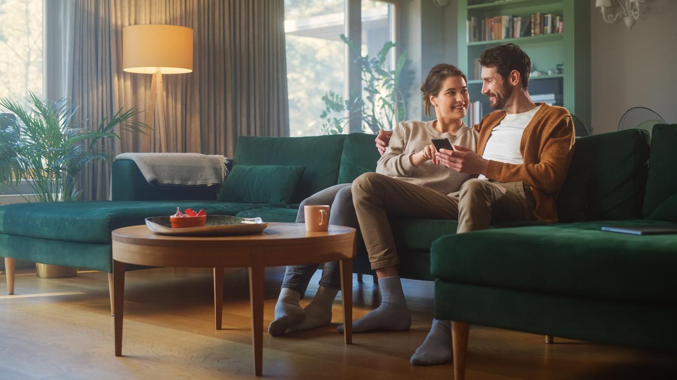 Couple cuddled up on a sectional couch, smiling at each other